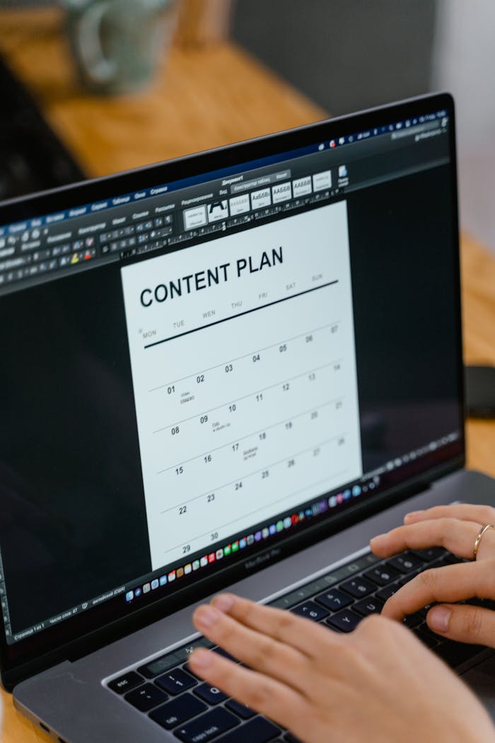 services-01 Close-up of hands typing on a laptop displaying a content plan document, ideal for business or marketing content.